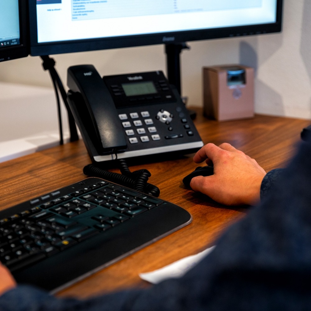 Een bureau met beeldscherm, toetsenbord en telefoon