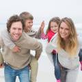 Gezin op het strand ouders met kinderen op hun rug